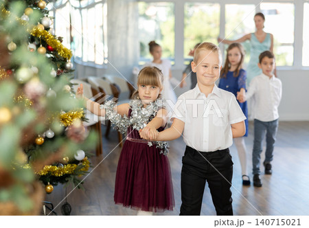 Christmas ball - group of children in festive clothes dances a waltz around New Year tree Christmas ball - group of children in festive clothes dances a waltz around New Year tree 140715021