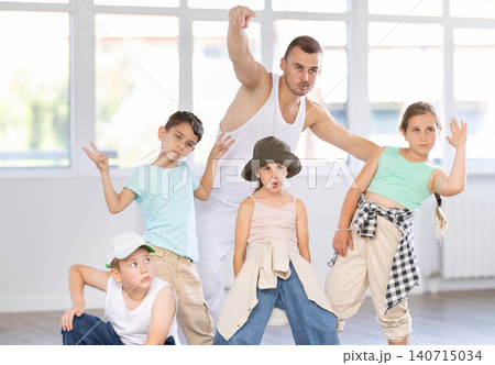Group portrait of happy preteen hip hop dancers with male choreographer in dance studio 140715034
