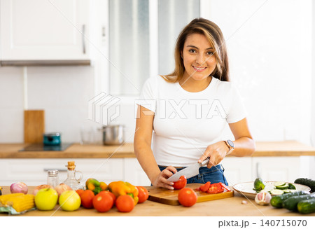 Smiling young Hispanic woman preparing salad in home kitchen Smiling young Hispanic woman preparing salad in home kitchen 140715070