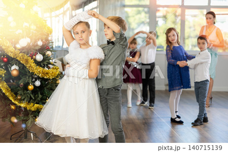 Little children practicing waltz dance in school-hall decorated with Christmas-tree Little children practicing waltz dance in school-hall decorated with Christmas-tree 140715139