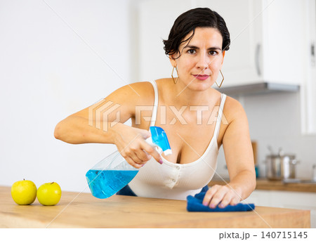 Positive woman keeping home clean and fresh during day, cleaning kitchen table 140715145