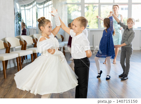 Little children in elegant dresses practicing waltz dance in school hall Little children in elegant dresses practicing waltz dance in school hall 140715150