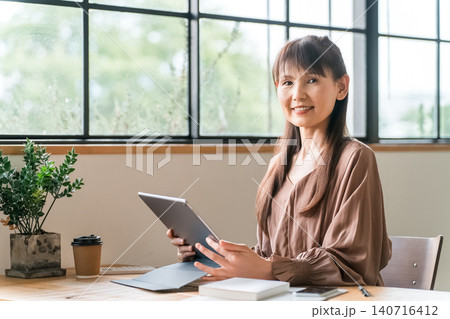 カフェでテレワーク・ノマドワークする中高年のアジア人女性 カフェでテレワーク・ノマドワークする中高年のアジア人女性 140716412