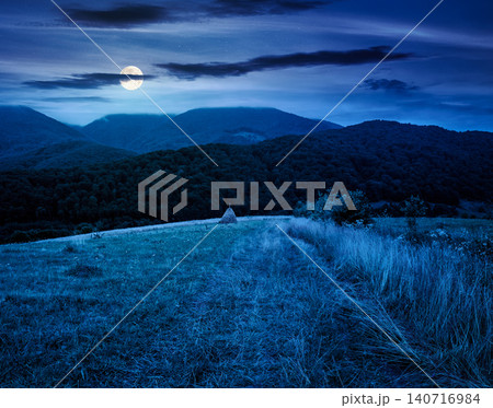 rural field on the hill at night. view in to the valley. countryside mountain landscape. full moon over alpine pasture near forested hills. inner strength to overcome fear, loneliness in darkness rural field on the hill at night. view in to the valley. countryside mountain landscape. full moon over alpine pasture near forested hills. inner strength to overcome fear, loneliness in darkness 140716984
