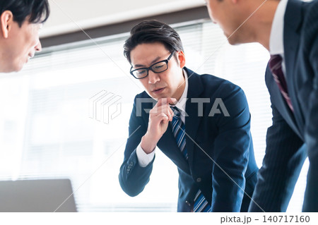 会議室で真剣に意見を交わすスーツ姿のビジネスマン3人 会議室で真剣に意見を交わすスーツ姿のビジネスマン3人 140717160