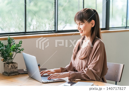 カフェでテレワーク・ノマドワークする中高年のアジア人女性 カフェでテレワーク・ノマドワークする中高年のアジア人女性 140717827