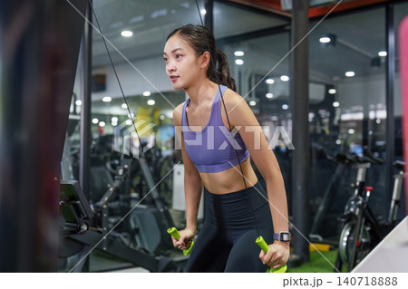 Asian woman doing cable pulldown exercise at gym for upper body strength Asian woman doing cable pulldown exercise at gym for upper body strength 140718888