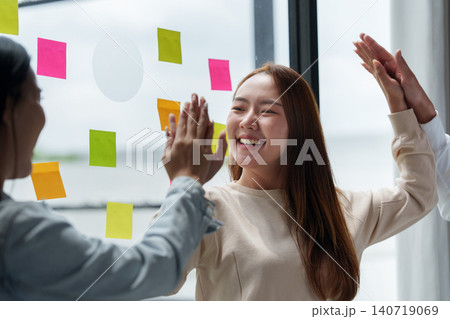 Asian women giving high five in office for teamwork and success Asian women giving high five in office for teamwork and success 140719069