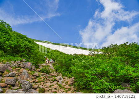 夏の晴天 白馬乗鞍岳への急登・ゴーロの岩場を歩く登山客の後ろ姿と雪原望む山岳風景� 140719122