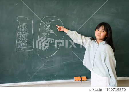 教室の黒板の前で笑顔で指差しをする高学年の女子小学生 教室の黒板の前で笑顔で指差しをする高学年の女子小学生 140719270
