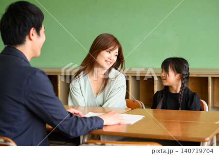 小学校の教室で先生と笑顔で和やかに三者面談(相談)をする母親と女の子 小学校の教室で先生と笑顔で和やかに三者面談(相談)をする母親と女の子 140719704