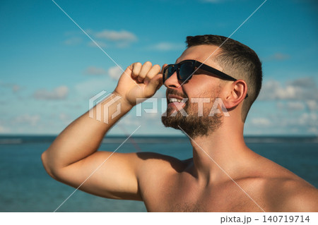 Man enjoys sunny day at the beach with sunglasses on Man enjoys sunny day at the beach with sunglasses on 140719714