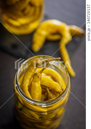 Pickled Banana Peppers in a Glass Jar With Olive Oil on Wooden Table Pickled Banana Peppers in a Glass Jar With Olive Oil on Wooden Table 140720137