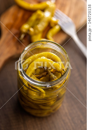 Pickled Banana Peppers in a Glass Jar With Olive Oil on Wooden Table Pickled Banana Peppers in a Glass Jar With Olive Oil on Wooden Table 140720138