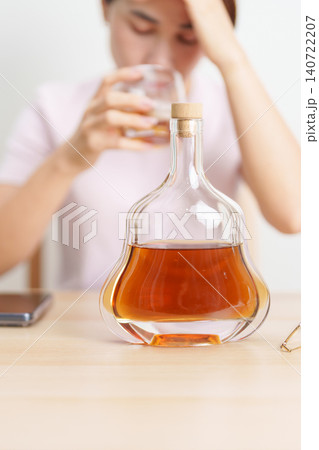 Stressed woman drinking cognac alone with problem. Exhausted drunk man looking stressed and sleepy. Alcohol addiction, Alcoholism, emotional distress and mental health concept Stressed woman drinking cognac alone with problem. Exhausted drunk man looking stressed and sleepy. Alcohol addiction, Alcoholism, emotional distress and mental health concept 140722207