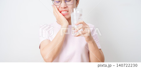 woman having toothache and pain after drink ice water for concept of Teeth Sensitive to Cold, Tooth Decay and Gum Disease, Grinding Teeth and Stress, Exposed Nerve Roots, Crack and Receding 140722230