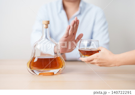 Man making stop hand gesture to refuse a glass of Cognac, Healthy man say no to alcohol drink, stop alcoholism and addiction concept. Responsible man reject a drink before driving and quit booze 140722291