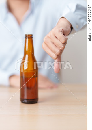 man show thumb down hand gesture to refuse a bottle of Beer, Healthy man say no to alcohol drink, stop alcoholism and addiction concept. Responsible man reject a drink before driving and quit booze 140722293