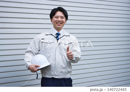 作業服を着てヘルメットを持つ笑顔の若い男性 作業服を着てヘルメットを持つ笑顔の若い男性 140722485