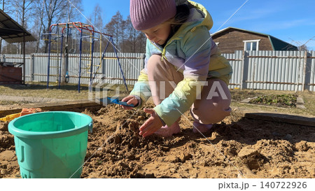 With sandy fingers and a big smile, the little girl decorates her newly built sandcastle with small pebbles and leaves she found nearby. With sandy fingers and a big smile, the little girl decorates her newly built sandcastle with small pebbles and leaves she found nearby. 140722926