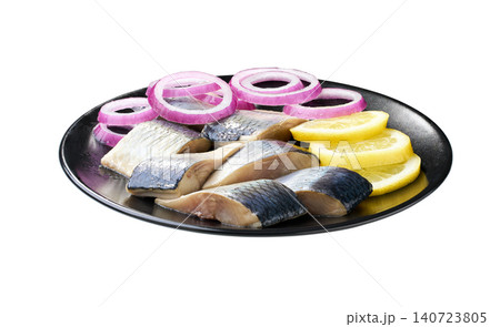 pieces of herring with red onion rings and lemon on a black plate isolated on a white background. pieces of herring with red onion rings and lemon on a black plate isolated on a white background. 140723805