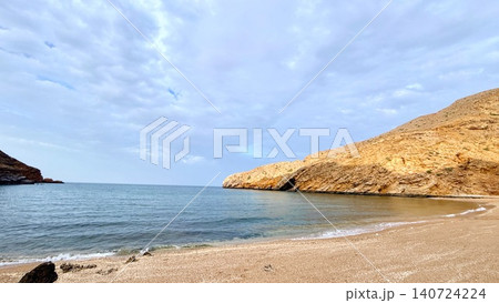 Secluded sandy bay with calm sea and rocky headlands under cloudy sky Secluded sandy bay with calm sea and rocky headlands under cloudy sky 140724224