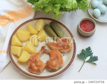 Quail schnitzel from legs on the plate and boiled potatoes with pickles. Quail schnitzel from legs on the plate and boiled potatoes with pickles. 140724738