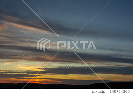 Dramatic sunset with colorful clouds over a vast landscape showcasing the beauty of nature during twilight hours 140724860