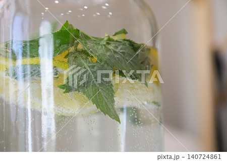 Refreshing lemon mint beverage in a clear glass jar with bubbles captured in a bright indoor setting Refreshing lemon mint beverage in a clear glass jar with bubbles captured in a bright indoor setting 140724861