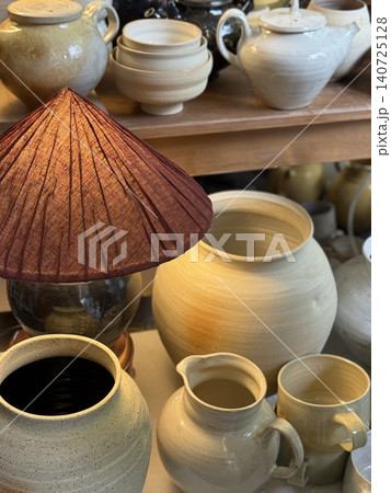 Ceramic pottery with various shapes and sizes displayed alongside lamp in rustic setting Ceramic pottery with various shapes and sizes displayed alongside lamp in rustic setting 140725128