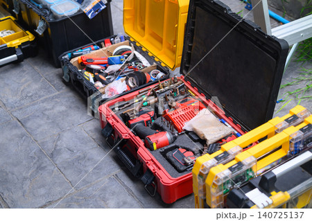 Open Toolboxes with Power Drill and Hand Tools on Concrete Floor at Construction Site 140725137