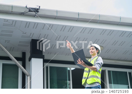Asian Engineer Using Drone for Building Inspection While Holding Laptop Outdoors Asian Engineer Using Drone for Building Inspection While Holding Laptop Outdoors 140725193