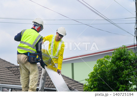 Two Technicians Installing Solar Panel on Residential Rooftop in Safety Gear Two Technicians Installing Solar Panel on Residential Rooftop in Safety Gear 140725194
