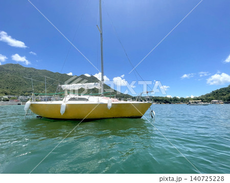 Yellow sailboat anchored in clear turquoise water under a bright blue sky Yellow sailboat anchored in clear turquoise water under a bright blue sky 140725228
