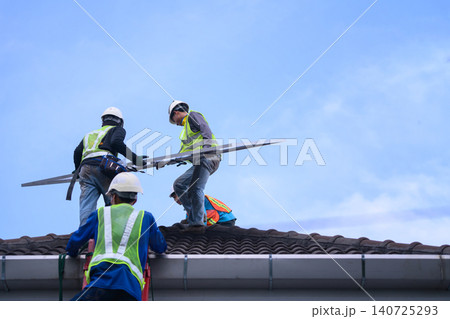 Solar Panel Installation Workers on Residential Rooftop Against Blue Sky Solar Panel Installation Workers on Residential Rooftop Against Blue Sky 140725293