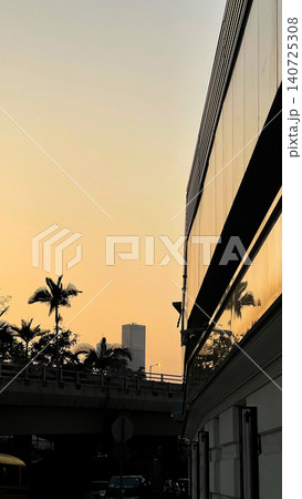 Golden hour cityscape with modern architecture and palm trees silhouetted against the sky Golden hour cityscape with modern architecture and palm trees silhouetted against the sky 140725308