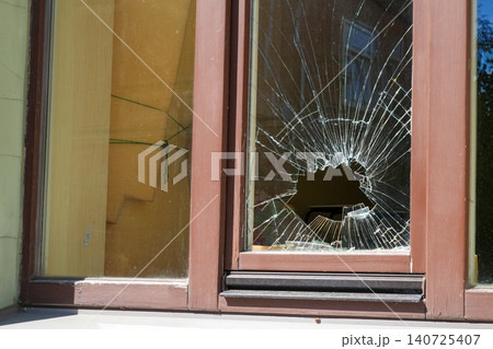 Broken Residential Window With Large Impact Hole and Cracked Glass After Vandalism or Accident Broken Residential Window With Large Impact Hole and Cracked Glass After Vandalism or Accident 140725407