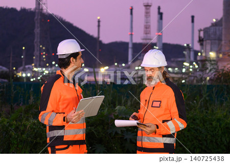 Engineers discussing inspection work outside oil refinery and petrochemical processing facility Engineers discussing inspection work outside oil refinery and petrochemical processing facility 140725438