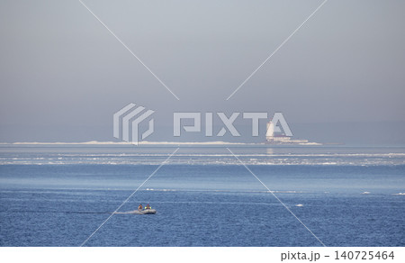 Small boat with fishermen crosses a calm, icy winter Baltic sea Small boat with fishermen crosses a calm, icy winter Baltic sea 140725464