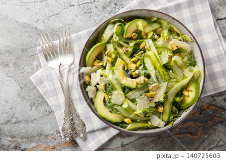 Freshly mixed greens salad with shaved asparagus, parmesan, pistachios, avocado and arugula closeup in the plate. Horizontal top view Freshly mixed greens salad with shaved asparagus, parmesan, pistachios, avocado and arugula closeup in the plate. Horizontal top view 140725603