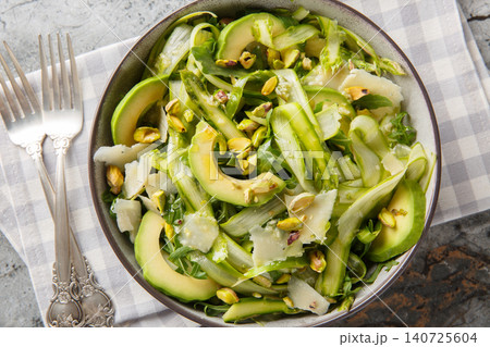 Gourmet salad with shaved asparagus, parmesan, pistachios, avocado and arugula closeup in the plate. Horizontal top view 140725604