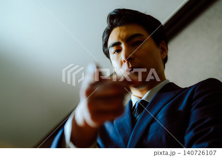指差しで指示を出すスーツ姿の男性 指差しで指示を出すスーツ姿の男性 140726107