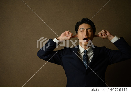 耳を塞いで叫ぶスーツ姿の男性 140726111
