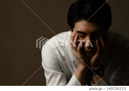 両手で顔を覆い目を閉じる男性 両手で顔を覆い目を閉じる男性 140726113