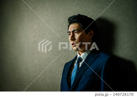 壁に寄りかかるスーツ姿の日本人男性 壁に寄りかかるスーツ姿の日本人男性 140726170