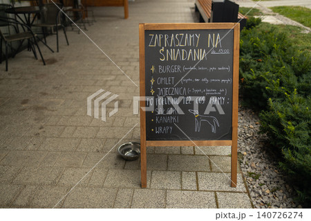 Chalkboard menu stand outside cozy cafe on city street 140726274