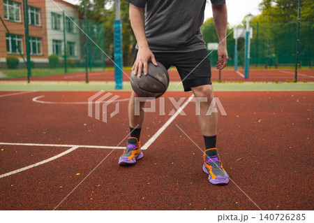 Cropped view of man dribbling basketball on court 140726285