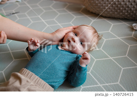 Loving mother's hands gently cradling her baby boy's head Loving mother's hands gently cradling her baby boy's head 140726415