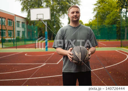 Portrait of young man holding basketball ball on court 140726444