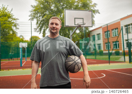 Portrait of young man holding basketball ball on court Portrait of young man holding basketball ball on court 140726465
